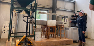 woman stands beside chestnut milling machine at Rural Action