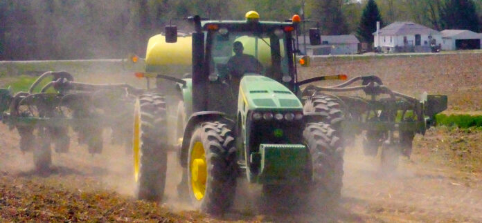 header_Ben in the cab of the John Deere tractor plowing field kicking up dust
