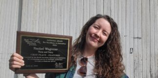 a woman stands holding an awards plaque