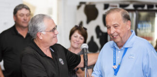 two white men shake hands behind a lecturn