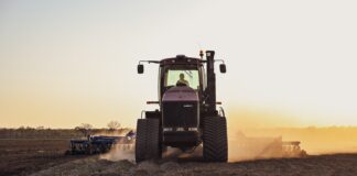 a tractor in a field with dust trailing it