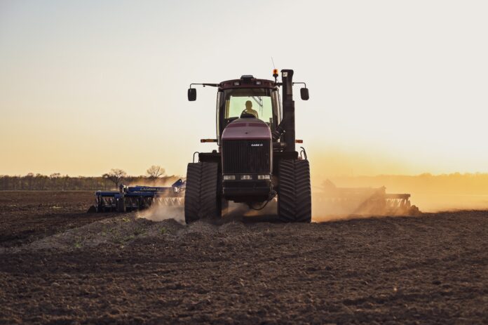Photo by Loren King a tractor in a field with dust trailing it