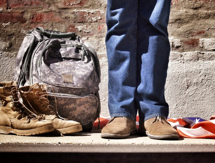 Photo by Benjamin Faust minimalist photography of person standing near backpack and boots