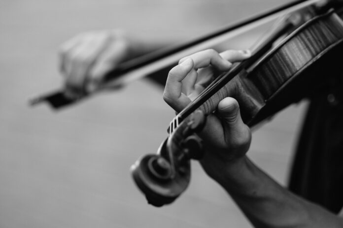Photo by Joel Wyncott grayscale photo of person playing violin