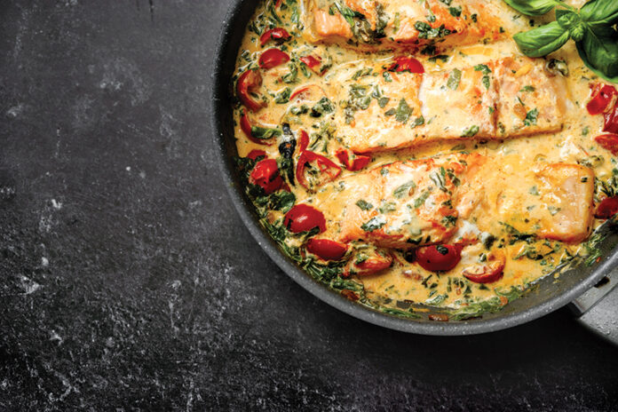 Close up of delicious tuscan cream salmon with spinach in a pan
